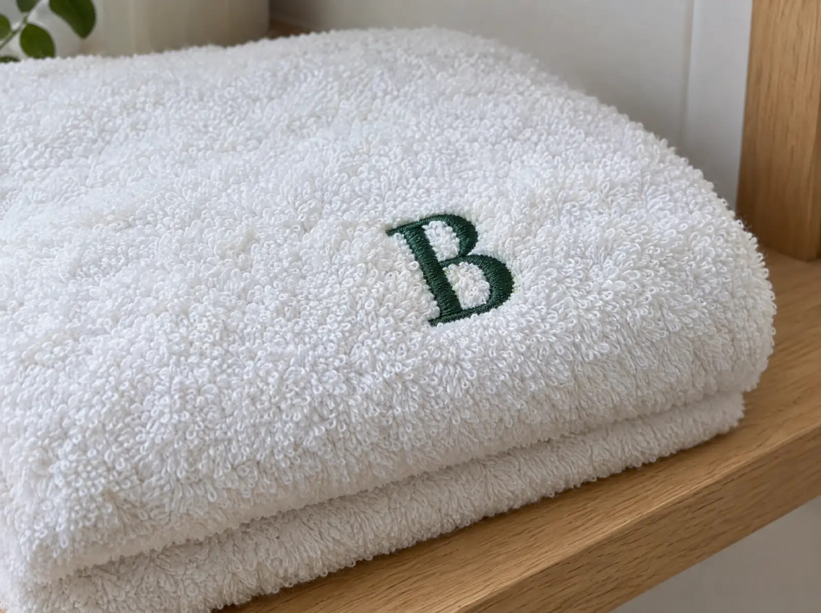 A white terry towel with a green satin-stitch monogram letter sitting on top of the loops