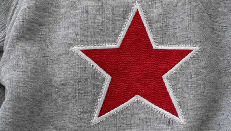 A grey sweatshirt with a red twill applique star stitched down with a satin border